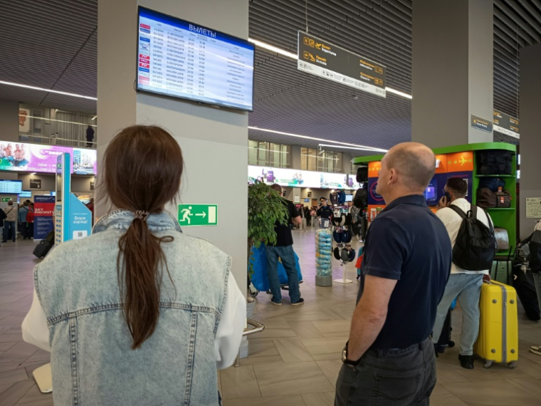 Des passagers regardent un panneau d'affichage des vols à l'aéroport de Kaliningrad, en Russie, le 4 juillet 2026 ( AFP / Guillaume DECAMME )