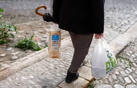 Une retraitée transporte un sac en plastique contenant des provisions et du pain tranché, alors qu'elle marche le long d'une rue à Ronda
