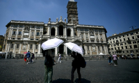 Des visiteurs se protègent du soleil avec des parapluies lors d'une vague de chaleur, le 11 août 2025 à Rome ( AFP / Filippo MONTEFORTE )