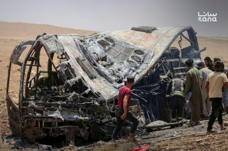 Cette photo prise et diffusée par l’agence de presse officielle syrienne SANA le 25 juillet 2026 montre des personnes et des secouristes inspectant les dégâts sur les lieux de la collision meurtrière entre deux bus sur la route reliant Damas à Deir Ezzor ( SANA / - )