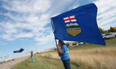Des séparatistes agitent le drapeau de l'Alberta au bord de la route, lors d'un événement en faveur de la séparation de cette province d'avec le Canada, à Dunmore, dans le sud-est de l'Alberta, le 23 septembre 2026 ( AFP / ABED ZAQ )