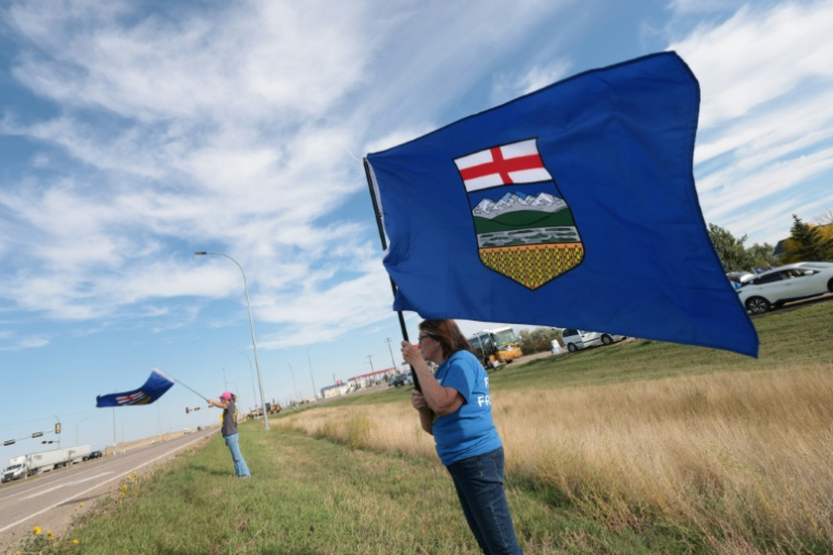 Des séparatistes agitent le drapeau de l'Alberta au bord de la route, lors d'un événement en faveur de la séparation de cette province d'avec le Canada, à Dunmore, dans le sud-est de l'Alberta, le 23 septembre 2026 ( AFP / ABED ZAQ )