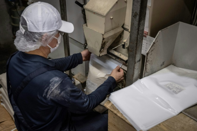 Un employé emballe du riz pour l'exportation vers les États-Unis dans un magasin à Tokyo, le 9 juillet 2025 ( AFP / Yuichi YAMAZAKI )