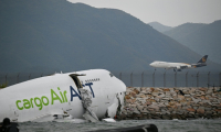 Un avion cargo Boeing dans l'eau après être sorti de piste lors de son atterrissage à l'aéroport international de Hong Kong, le 20 octobre 2025 ( AFP / Peter PARKS )