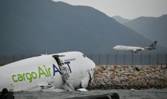 Un avion cargo Boeing dans l'eau après être sorti de piste lors de son atterrissage à l'aéroport international de Hong Kong, le 20 octobre 2025 ( AFP / Peter PARKS )