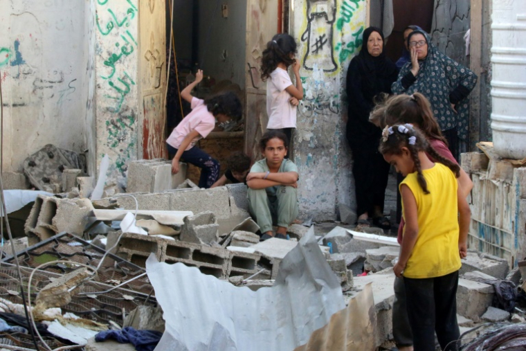 Des femmes et des enfants palestiniens au milieu des décombres d'une maison après une frappe israélienne sur le camp de Nousseirat, dans le centre de la bande de Gaza, le 27 septembre 2025  ( AFP / Eyad BABA )