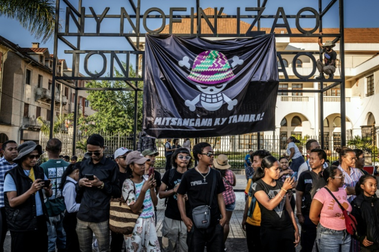 Des habitants se rassemblent alors que des jeunes installent une banderole portant la version malgache du logo du populaire manga japonais One Piece, un symbole adopté par les mouvements Gen Z à travers le monde, à Antananarivo le 12 octobre 2025 ( AFP / Luis TATO )