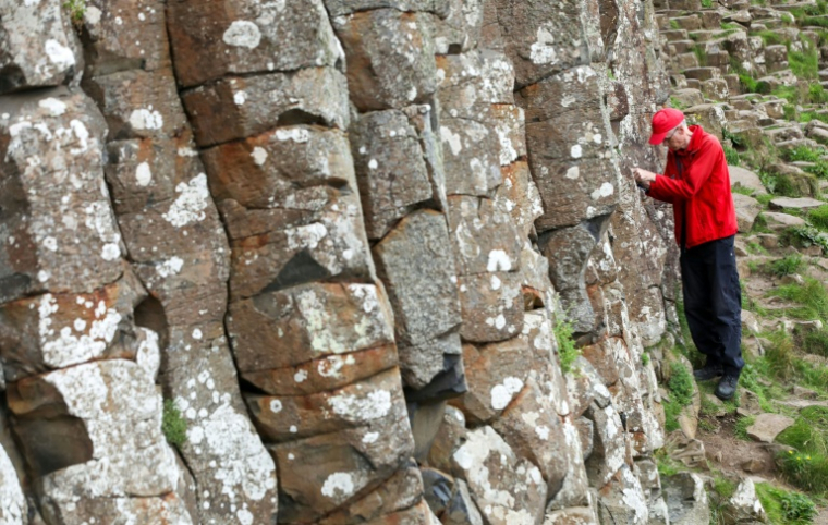 Cliff Henry, du National Trust, recherche des pièces de monnaie rouillées laissées par les touristes sur le site de la Chaussée des Géants près de Bushmills en Irlande du Nord, le 8 juillet 2025 ( AFP / PAUL FAITH )