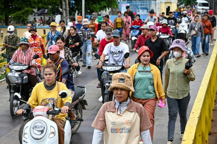 Des ouvriers de l'habillement sortent de leur usine pendant leur pause déjeuner à Phnom Penh, au Cambodge, le 8 juillet 2025. ( AFP / TANG CHHIN Sothy )