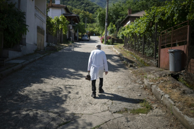 Le docteur Apostolov, médecin généraliste de 90 ans, gravit une rue escarpée de Skrat, un village situé au pied du massif de la Belassitsa en Bulgarie, le 15 juillet 2026 ( AFP / Nikolay DOYCHINOV )