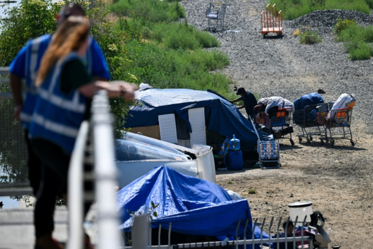 Des employés d'une association d'aide aux sans-abris veillent sur un campement de SDF, à Los Angeles, le 1er juin 2026 ( AFP / Patrick T. Fallon )