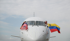 Les pilotes du vol 3599 d'American Airlines, reliant l'aéroport international de Miami à Caracas, au Venezuela, agitent des drapeaux vénézuéliens et américains avant de décoller pour un vol direct vers le Venezuela, le premier entre les États-Unis et le Venezuela en sept ans, le 30 avril 2026 à l'aéroport international de Miami, en Floride ( AFP / CHANDAN KHANNA )
