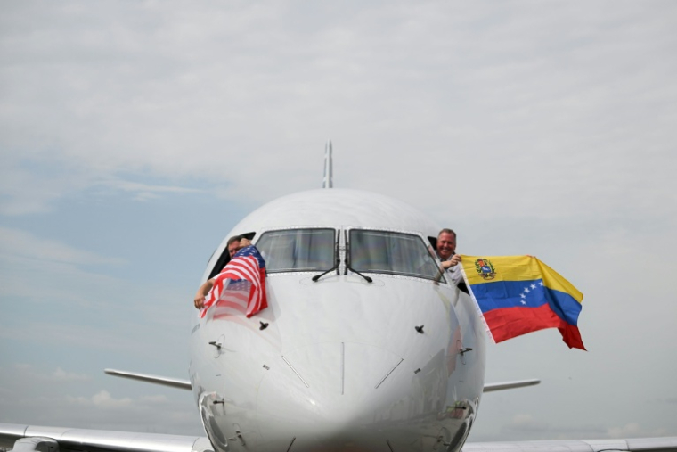 Les pilotes du vol 3599 d'American Airlines, reliant l'aéroport international de Miami à Caracas, au Venezuela, agitent des drapeaux vénézuéliens et américains avant de décoller pour un vol direct vers le Venezuela, le premier entre les États-Unis et le Venezuela en sept ans, le 30 avril 2026 à l'aéroport international de Miami, en Floride ( AFP / CHANDAN KHANNA )