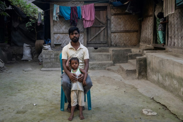 Mizan Hossain, blessé sur un chantier de démantèlement de bateaux, et son fils devant leur maison, le 19 février 2025 à Chittagong, au Bangladesh ( AFP / Munir UZ ZAMAN )