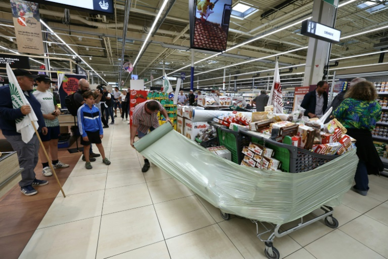 Des membres des syndicats agricoles FDSEA 72 et Jeunes Agriculteurs (JA) enveloppent des produits des produits contenant de l'acétamipride, un pesticide néonicotinoïde, retirés des rayons lors d'une opération de protestation dans un supermarché de Mundolsheim, le 20 août 2025 dans le Bas-Rhin ( AFP / Frederick FLORIN )