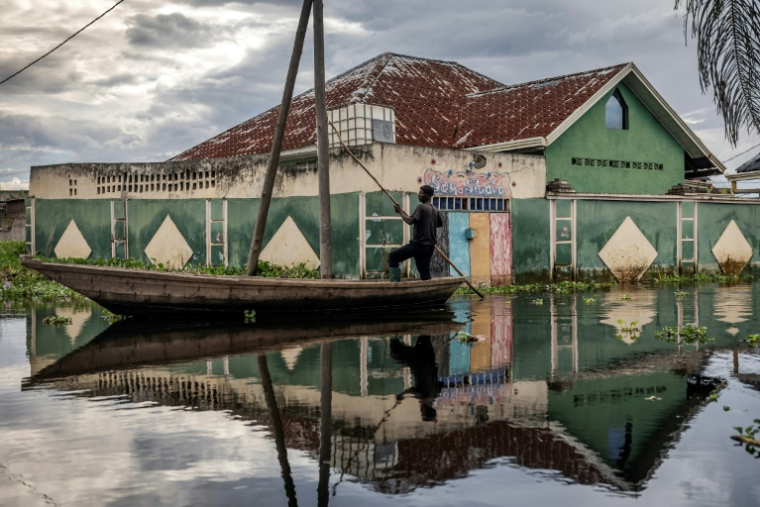 Un homme traverse en pirogue un quartier inondé de Gatumba, au Burundi, le 9 mai 2025 ( AFP / Luis TATO )