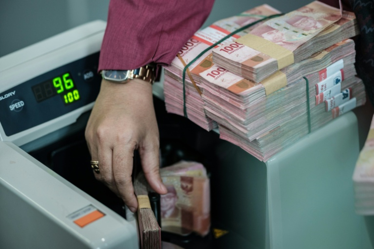 Un homme compte des billets de roupies dans un bureau de change à Jakarta en Indonésie le 4 juin 2026 ( AFP / Yasuyoshi Chiba )