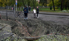Des personnes se tiennent près d'un cratère causé par un missile, à proximité d'une école endommagée à la suite d'une attaque russe à Kiev, le 19 octobre 2026 ( AFP / Sergei SUPINSKY )