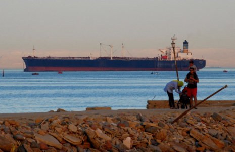 Des gens marchent sur la plage alors qu'un porte-conteneurs traverse le golfe de Suez en direction de la mer Rouge à Ain Soukhna