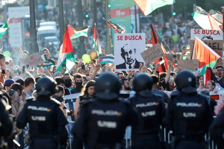 Des manifestants propalestiniens brandissent une pancarte avec un portrait du Premier ministre israélien Benjamin et la mention "Recherché", après avoir envahi les rues pendant la 21e et dernière du Tour d'Espagne cycliste, le 14 septembre 2025 ( AFP / Oscar DEL POZO )