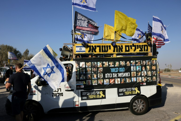 Une camionnette sur laquelle sont accrochés des photos d'otages israéliens ainsi que des drapeaux garée lors d'une manifestation  près du kibboutz Beeri, dans le sud d'Israël, appelant à la libération des otages retenus à Gaza, le 20 août 2025 ( AFP / AHMAD GHARABLI )