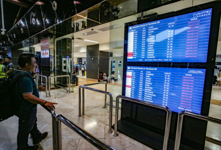 Un voyageur à l'aéroport Soekarno-Hatta de Tangerang après l'éruption du volcan Anak Krakatoa consulte le tableau des départs pour connaître le statut des vols, le 6 septembre 2026 en Indonésie ( AFP / Syarief Akbar )