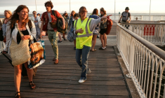 Une bénévole donne des instructions aux vacanciers de Lège-Cap-Ferret à leur arrivée à Arcachon par bateau, lors d'une opération d'évacuation de l'ensemble de la presqu'île du Cap-Ferret, dans le sud-ouest de la France, le 24 juillet 2026 ( AFP / ROMAIN PERROCHEAU )
