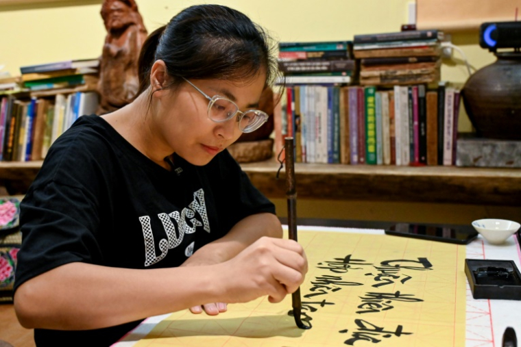 Hoang Thi Thanh Huyen apprend la calligraphie chez le calligraphe Nguyen Thanh Tung, le 15 mai 2025 à Hanoï, au Vietnam ( AFP / Nhac NGUYEN )