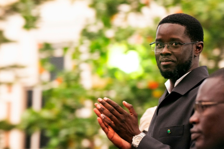 Le président sénégalais Bassirou Diomaye Faye applaudit depuis le toit ouvrant de son véhicule à l'issue d'une cérémonie de lancement de Kiiraay, son nouveau parti, dans le quartier des Almadies à Dakar, le 25 juillet 2026 ( AFP / SEYLLOU )