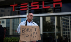 Une personne manifeste contre Tesla et Elon Musk devant une concession Tesla à Lisbonne