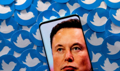 Photo d'illustration du visage d'Elon Musk sur un smartphone devant des logos Twitter