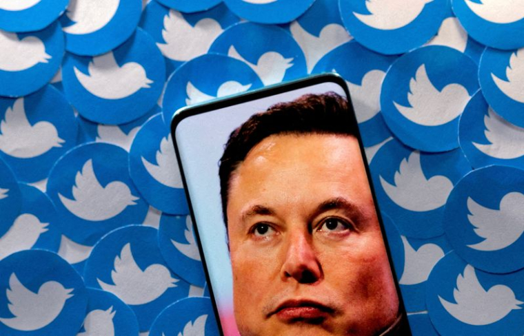 Photo d'illustration du visage d'Elon Musk sur un smartphone devant des logos Twitter