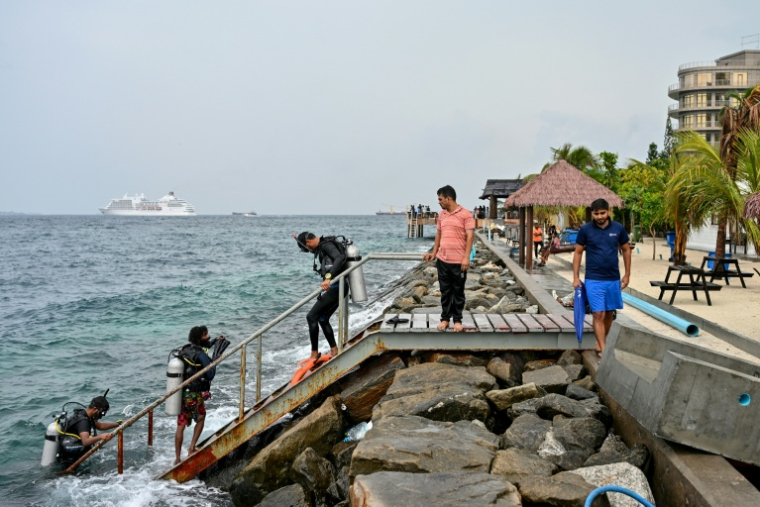 Un touriste, accompagné de guides, revient d'une plongée en mer ouverte près de la plage de Rasfannu à Malé, le 15 mai 2026 ( AFP / Mohamed Afrah )