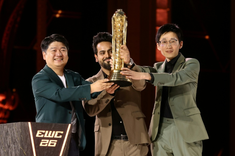 Le dirigeant de l'équipe chinoise All Gamers Le Kedeng (à gauche) brandit le trophée de l'Esports World Cup à Paris le 23 août 2026 ( POOL / Teresa SUAREZ )