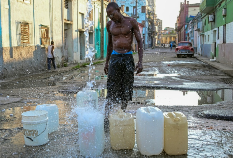 Un homme collecte de l'eau potable à un point de ravitaillement public dans une rue de La Havane, le 6 octobre 2026 ( AFP / YAMIL LAGE )