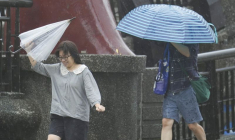 Des personnes tiennent des parapluies alors que le typhon Kong-rey approche à Keelung