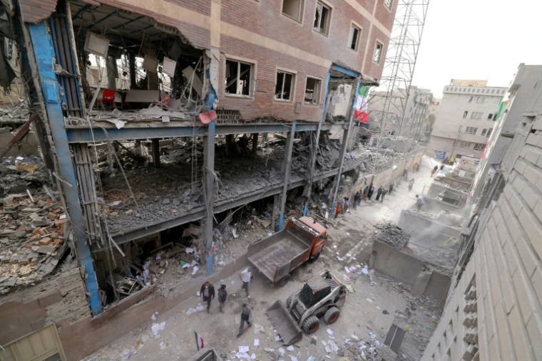 Des ouvriers iraniens déblaient les gravats d'habitations détruites, le 15 mars 2026 à Téhéran ( AFP / Atta KENARE )