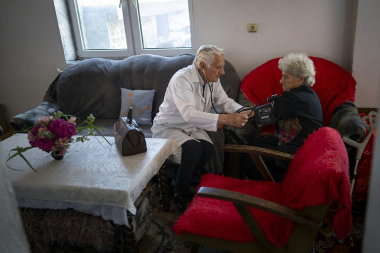 Le docteur Apostolov, médecin généraliste de 90 ans, mesure la tension d'une patiente dans le village de Skrat, situé au pied du massif de la Belassitsa en Bulgarie, le 15 juillet 2026 ( AFP / Nikolay DOYCHINOV )