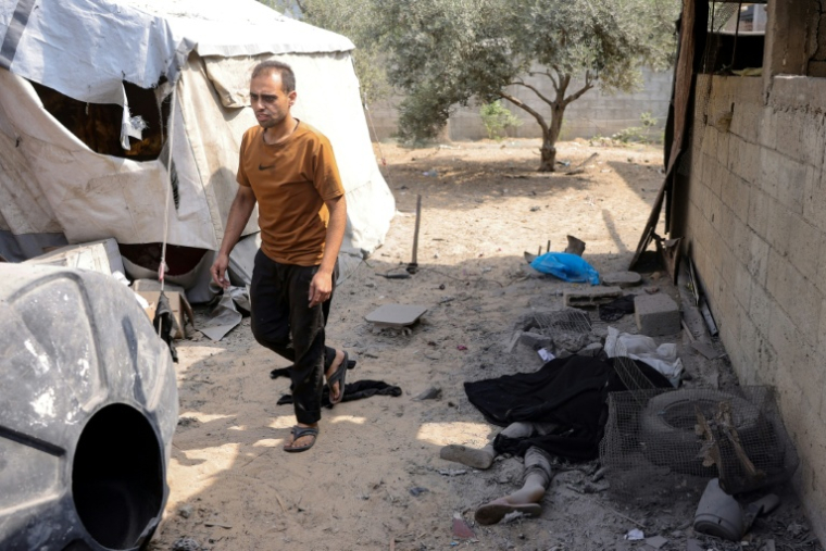 Un Palestinien passe près du coprs d'un victime d'une frappe israélienne sur le quartier Abou Iskandar dans le nord de Gaza-ville, pilonnée par l'armée israélienne avant une offensive annoncée au sol, le 22 août 2025 ( AFP / Bashar TALEB )