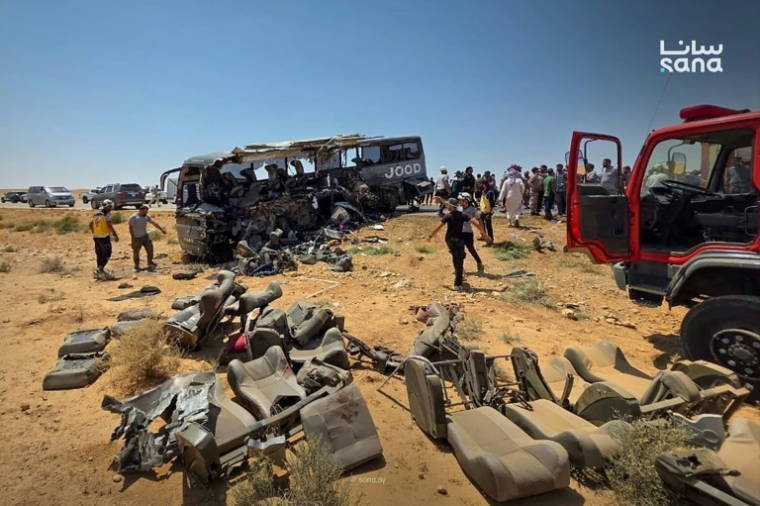 Cette photo prise et diffusée par l’agence de presse officielle syrienne SANA le 25 juillet 2026 montre des personnes et des secouristes inspectant les dégâts sur les lieux de la collision meutrière entre deux bus sur la route reliant Damas à Deir Ezzor ( SANA / - )