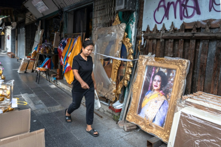 Une Thaïlandaise portant la couleur noire du deuil passe le 30 octobre 2025 à Bangkok devant un portrait de la reine mère Sirikit, décédée à 93 ans ( AFP / Chanakarn Laosarakham )
