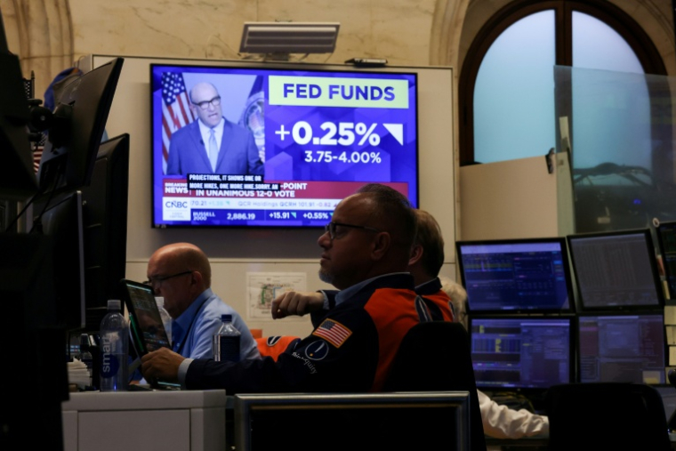 Des traders travaillent sous un écran de télévision annonçant la hausse des taux de la Réserve fédérale à la Bourse de New York le 16 septembre 2026 ( AFP / TIMOTHY A. CLARY )