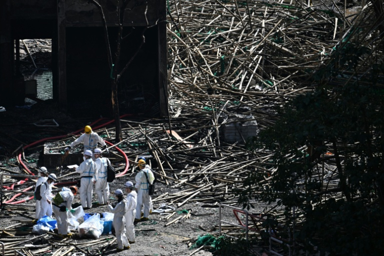 Des policiers de l'unité d'identification, équipés de combinaisons blanches, sur les lieux de l'incendie le 29 novembre 2025 at Wang Fuk Court, Hong Kong ( AFP / Philip FONG )