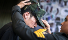 Un soldat thaïlandais met une casquette militaire sur la tête d'une nouvelle recrue, à la suite d'une loterie le 7 avril 2026 à Bangkok ( AFP / chanakarn LAOSARAKHAM )