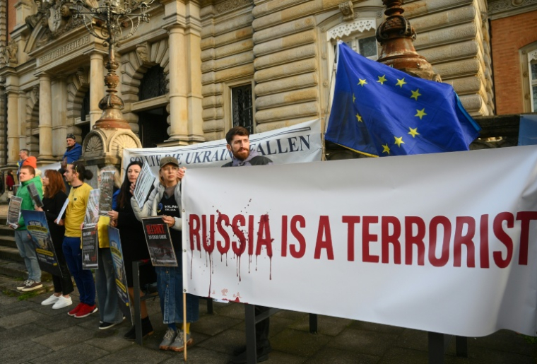 Des manifestants protestent avec des banderoles "la Russie est un terroriste" devant le tribunal où est jugé un ancien officien ukrainien à Hambourg (nord de l'Allemagne), le 14 octobre 2026 ( AFP / Gregor Fischer )