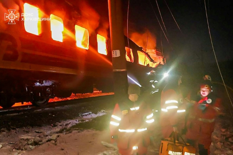 Photo prise et diffusée par les secours ukrainiens le 27 janvier 2026, montrant des secouristes ukrainiens près d'un train en flammes après une frappe russe dans la région de Kharkiv (nord-est de l'Ukraine) ( UKRAINIAN EMERGENCY SERVICE / Handout )