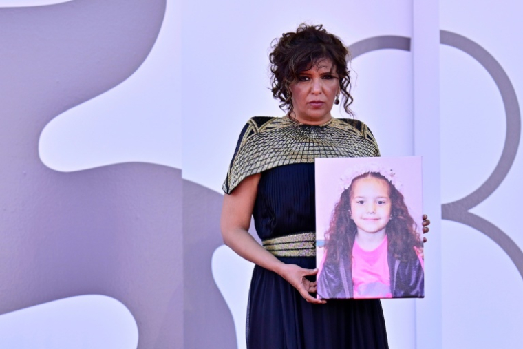 La réalisatrice Kaouther Ben Hania tenant un portrait de Hind Rajab, à la Mostra de Venise, le 3 septembre 2025 ( AFP / Tiziana FABI )
