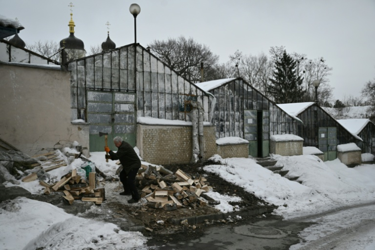 Le bénévole Volodymyr Vynogradov coupe du bois destiné à chauffer les serres du jardin botanique national Gryshko de l'Académie nationale des sciences d'Ukraine à Kievv, le 11 février 2026 ( AFP / Genya SAVILOV )
