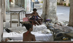 Une famille se repose sur des matelas dans l'entrée d'un immeuble, le long de l'avenue du Prado, lle 7 juillet 2026 à La Havae, lors d'une coupure de courant nationale à Cuba ( AFP / YAMIL LAGE )