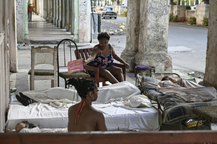 Une famille se repose sur des matelas dans l'entrée d'un immeuble, le long de l'avenue du Prado, le 7 juillet 2026 à La Havane, lors d'une penne de courant nationale à Cuba ( AFP / YAMIL LAGE )